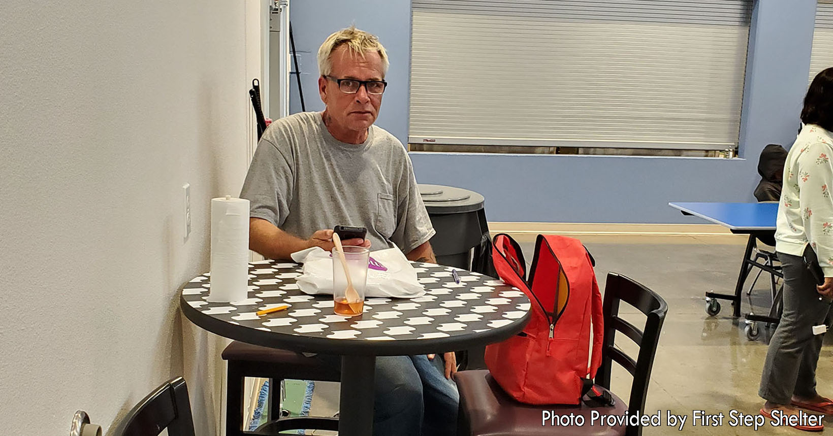This older gentleman has just finished eating his dinner. During this time, he is checking his cellphone to see if any job offers have come his way. Volunteers of the First Step Shelter help the residents create better resumes and apply for jobs.
