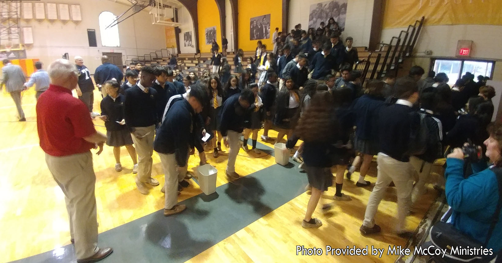 A group of young students are beginning to leave the bleachers after their assembly with Mike McCoy. Mike McCoy who is wearing his football jersey (left of the photo) was letting the students know how to face present and future challenges. Through faith, family, and friends, these students will be able to overcome any challenge.