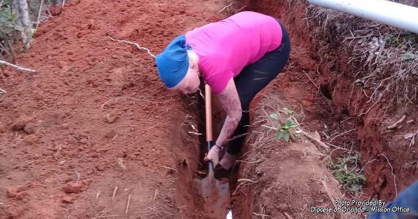One of the elder women is using a shovel to better the trench that was made for the pipeline. She is working hard like everyone else around her.