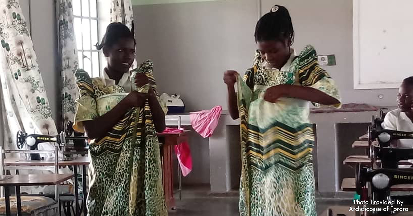 The young girls are in the workshop trying on clothes. These clothes are the ones they made with the skills they learned from tailoring.