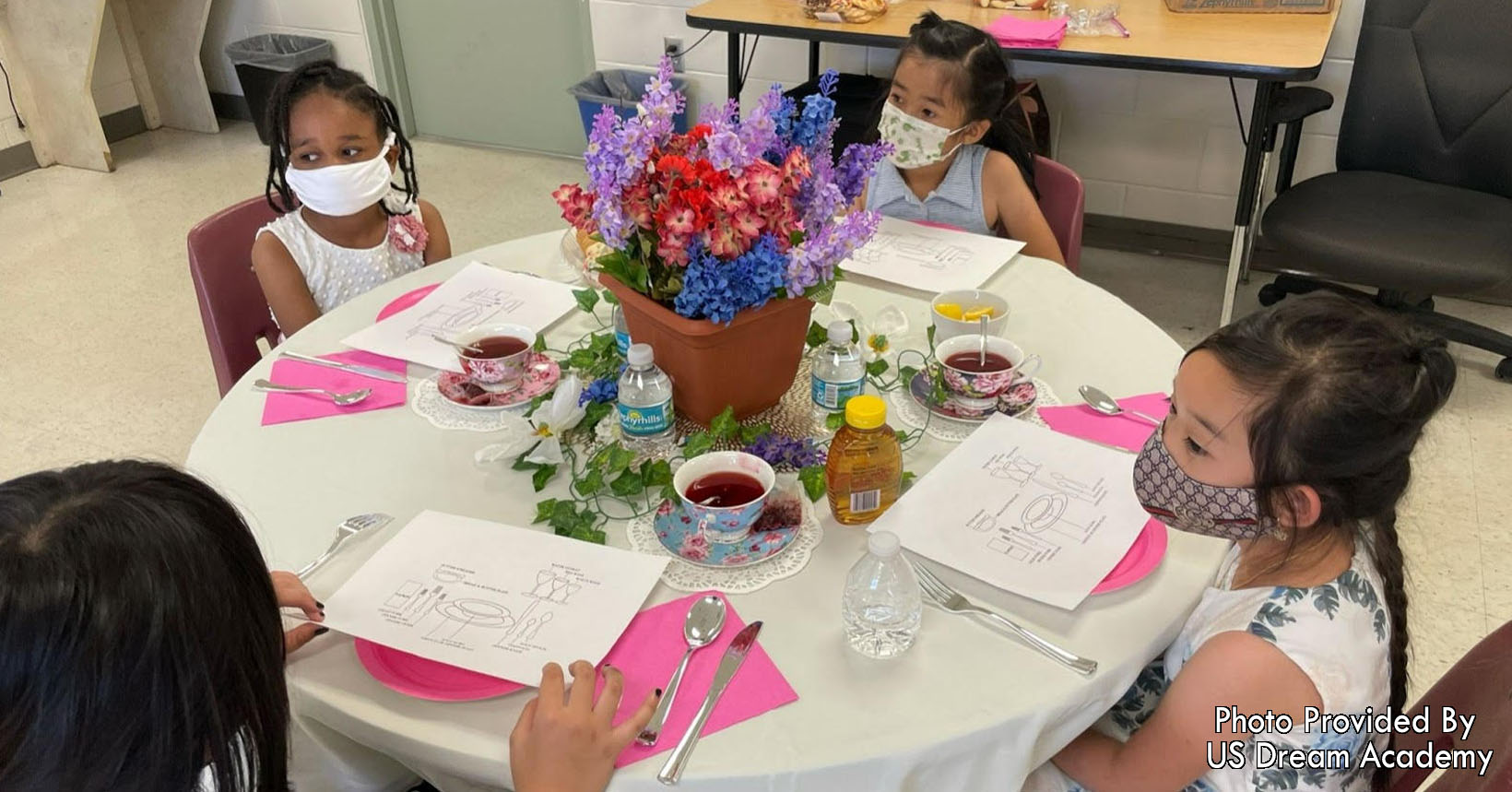Young children having a tea party to demonstrate table etiquette.