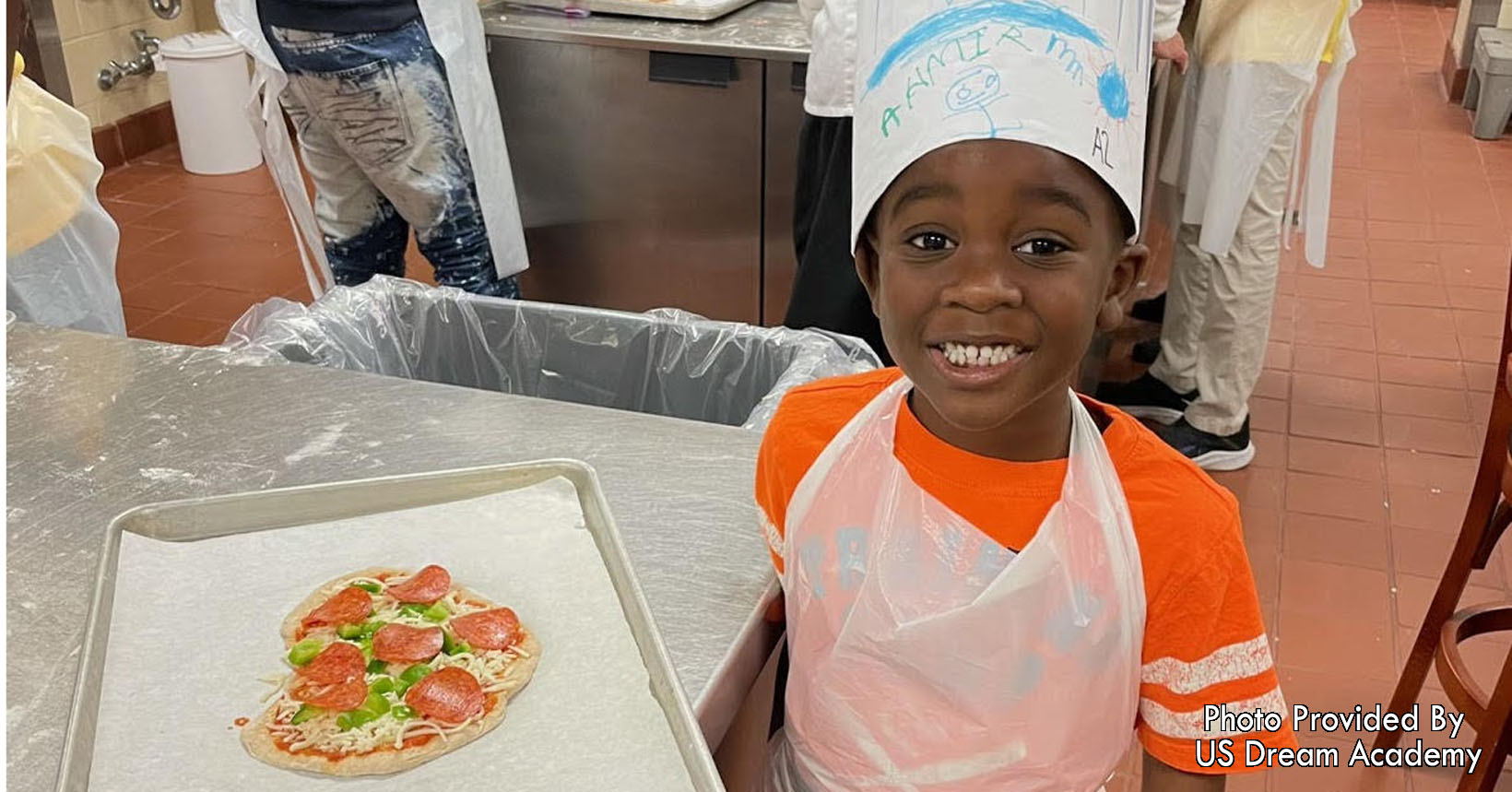 A young student learns culinary skills making his own pizza.